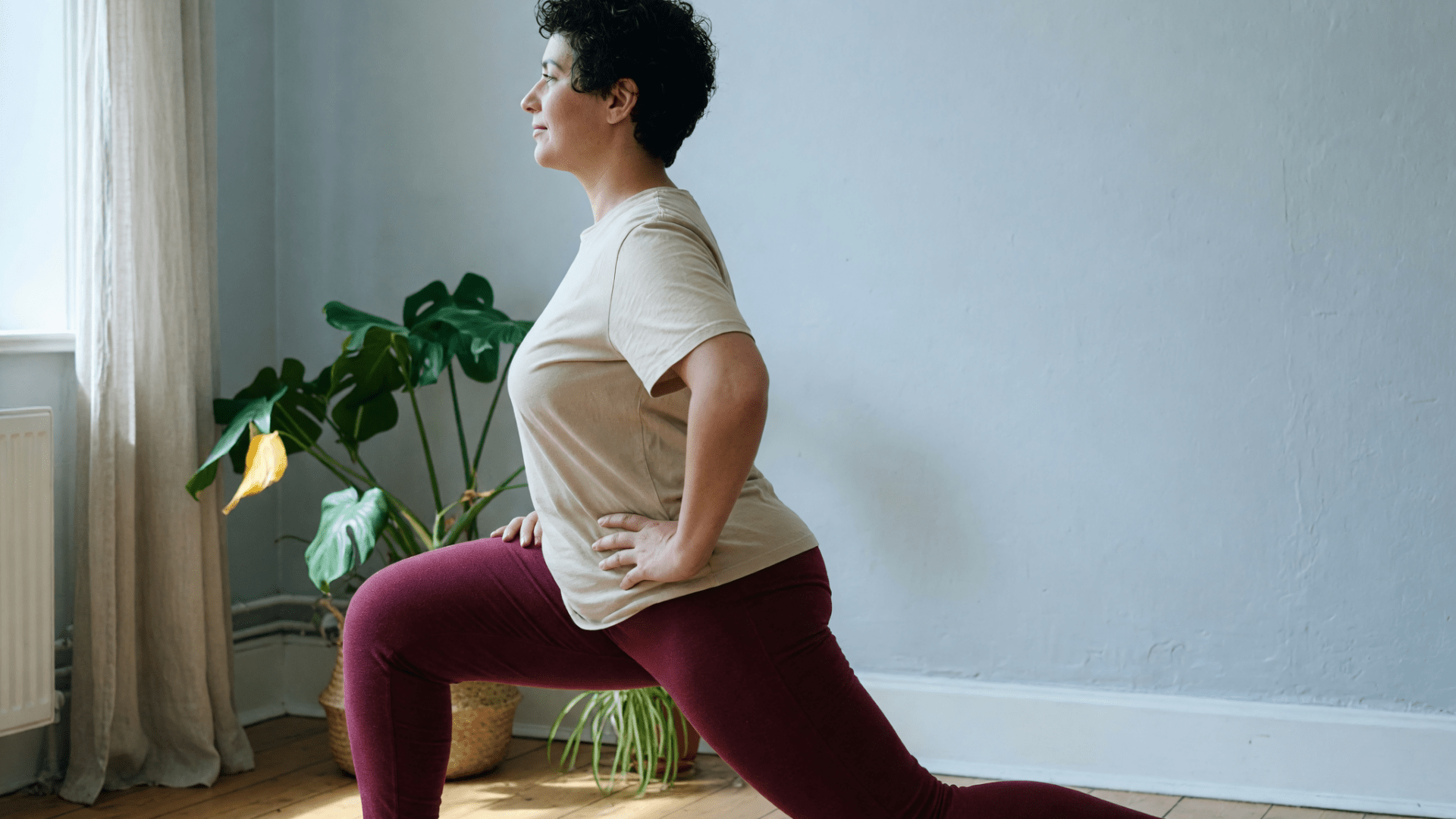 Femme en fente avant dans un salon, legging bordeaux et tee-shirt sable.