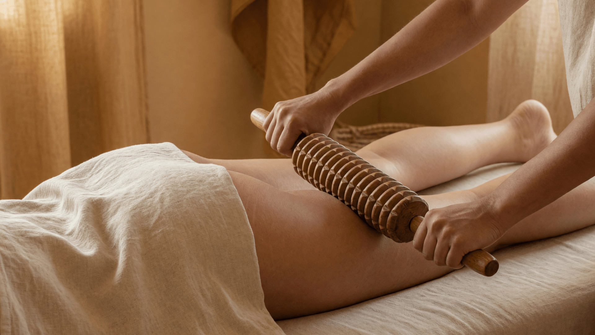 Un rouleau de bois strié passe sur la cuisse pendant un massage sur table.