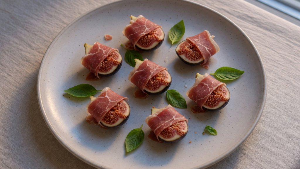 Des quartiers de figue entourés de jambon cru, avec quelques feuilles de basilic.