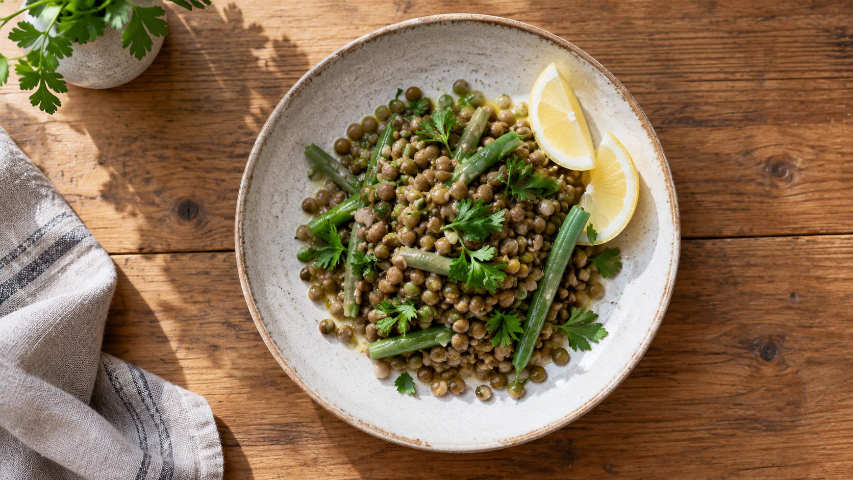 Une assiette de lentilles, de haricots verts et d'herbes, avec deux quartiers de citron.