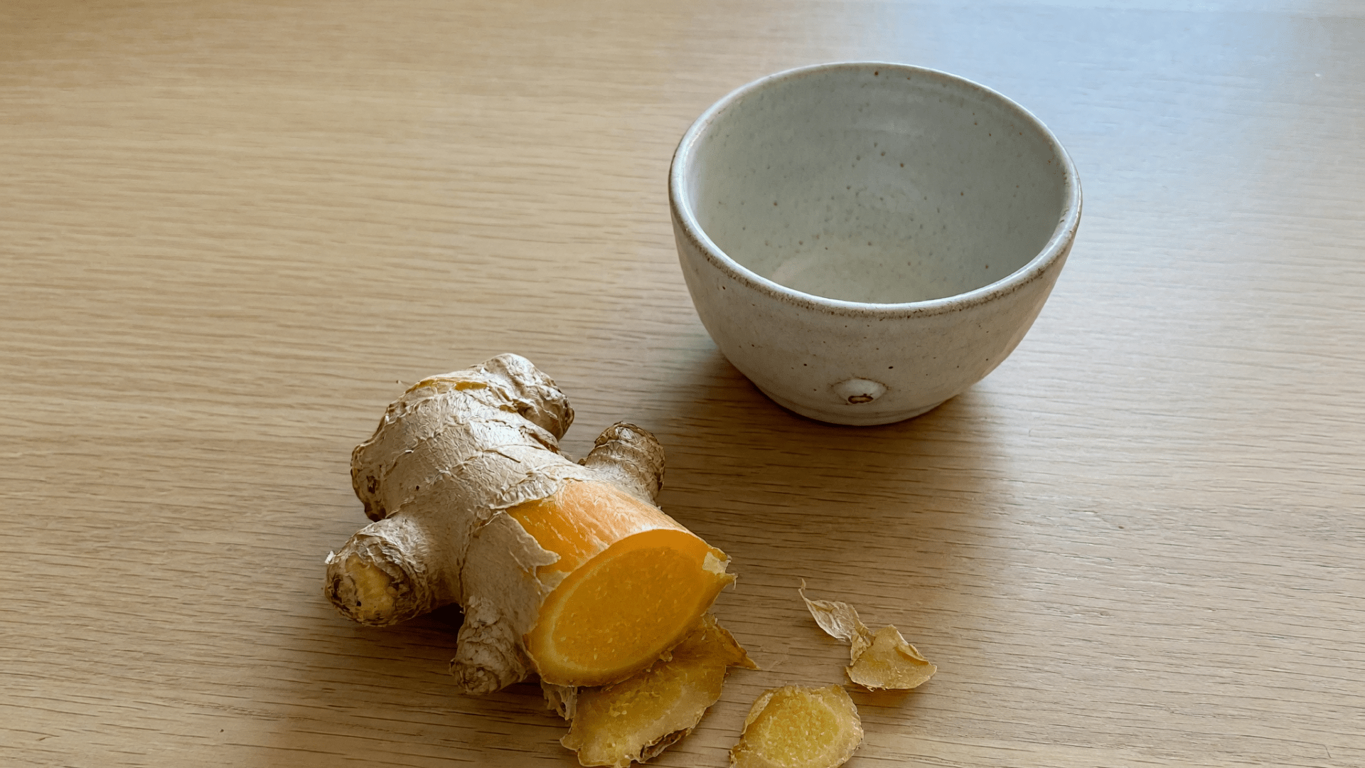 Racine de gingembre coupée, à côté d’un bol vide.